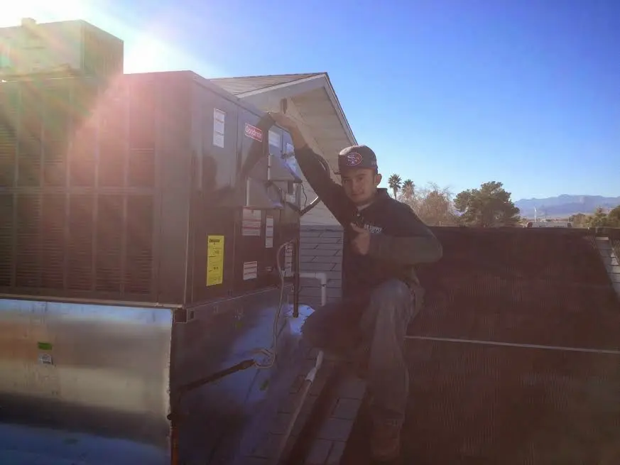 HVAC technician performing AC Tune-Up on a rooftop unit in Jennings